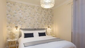 A bedroom with a bed, two bedside lamps, a nightstand, and a wall with a leaf pattern. - Apartment in Baveno with Lake Maggiore Views (Baveno)