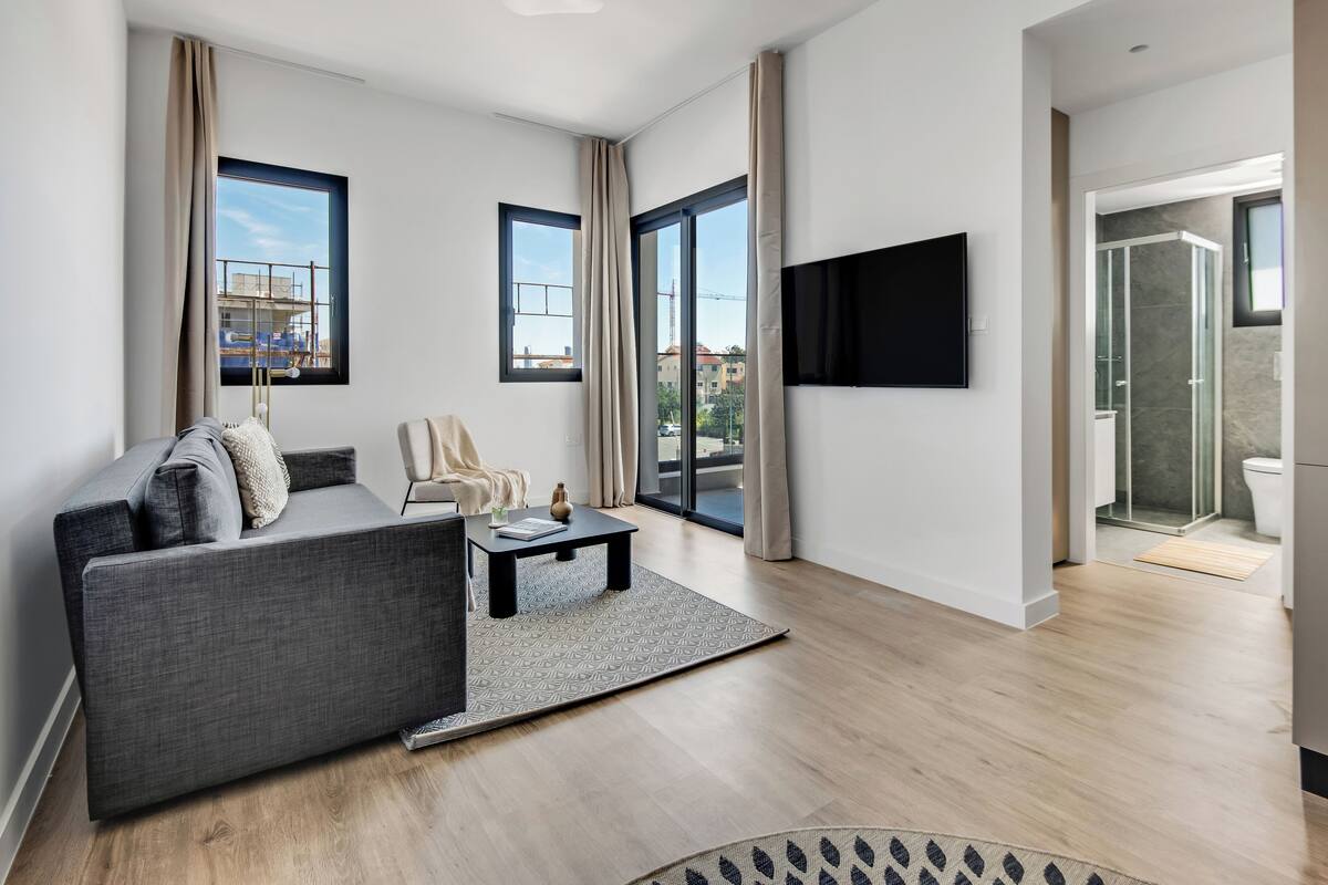 A modern living room with a grey sofa, a coffee table, and a TV mounted on the wall.