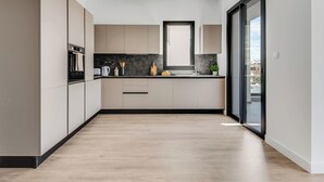 A modern kitchen with a built-in oven, a sink, and a window above the countertop. - Sanders Crystal 2 Limassol (Limassol)
