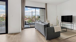 A modern living room with a grey sofa, a glass coffee table, and a flat-screen TV on a stand. - Sanders Crystal 2 Limassol (Limassol)