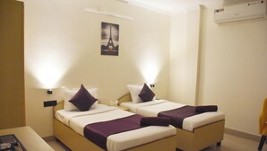 A hotel room with two beds, a nightstand, a chair, and a painting of the Eiffel Tower. - Date Palm Hotel (Gurugram)