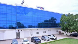 A modern building with a blue glass facade and a sign reading "DATE PALM". - Date Palm Hotel (Gurugram)