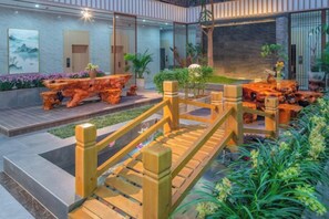 A modern outdoor area with a wooden bridge, seating, and a koi pond.