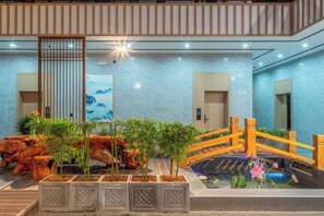 A hotel lobby with a wooden bridge, a koi pond, and a rock garden. - Jibolong Hotel (Lijiang)