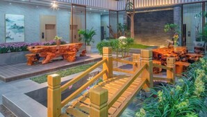 A modern hotel lobby with a wooden staircase, a koi pond, and a reception desk. - Jibolong Hotel (Lijiang)
