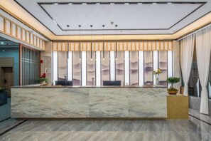 A reception area with a marble counter, a large window with curtains, and a modern ceiling design. - Jibolong Hotel (Lijiang)