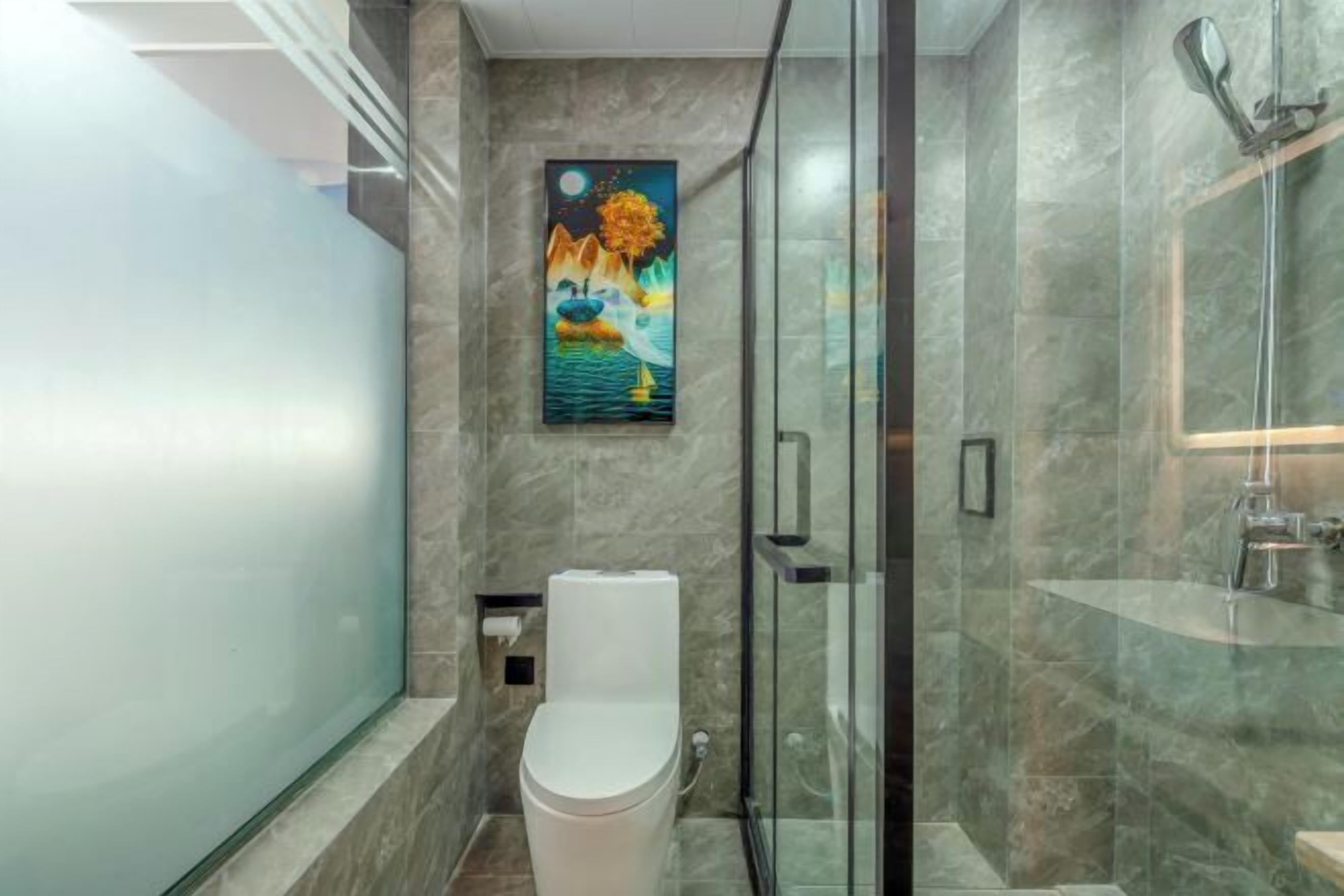 A modern bathroom with a glass shower enclosure, a toilet, and a marble wall.