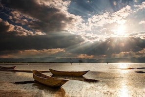 A calm body of water with boats and a person in the distance. - Jibolong Hotel (Lijiang)