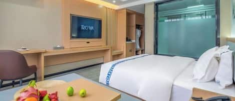 A hotel room with a bed, a desk, a television, and a fruit bowl.