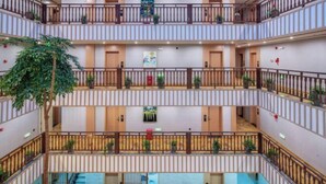 A multi-level hotel atrium with balconies, indoor plants, and a central open space. - Jibolong Hotel (Lijiang)
