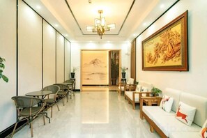 A hotel lobby with a reception desk, seating area, and a large painting on the wall. - Jibolong Hotel (Lijiang)