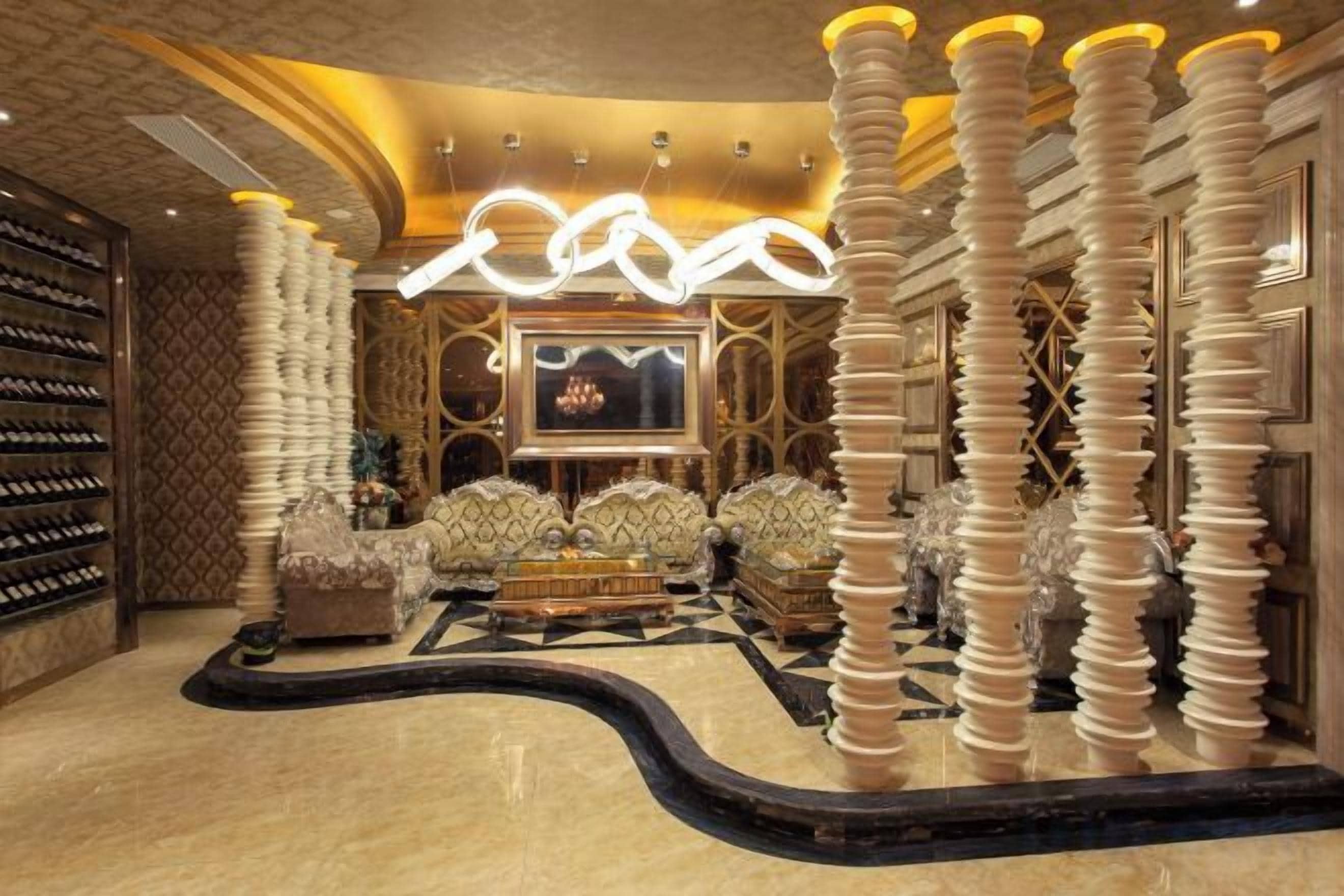 A luxurious lobby with a curved floor, a large chandelier, and a seating area with plush sofas.