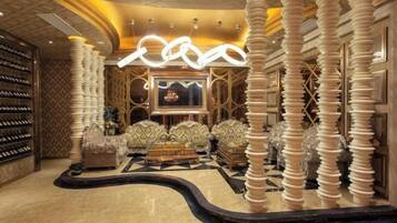 A luxurious lobby with a curved floor, a large chandelier, and a seating area with plush sofas.