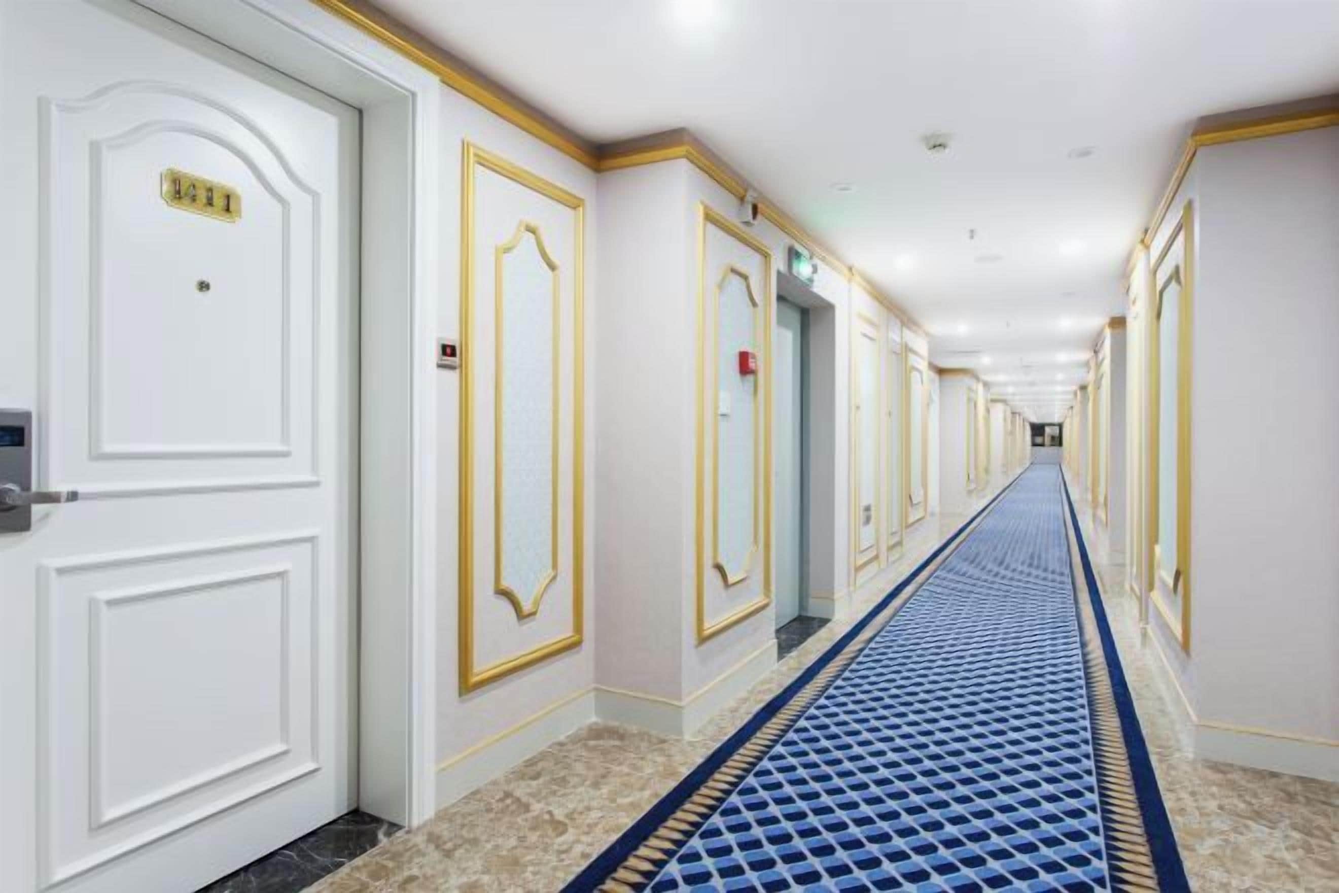 A hotel hallway with white doors, gold trim, and a blue carpet.