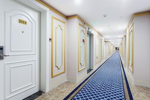 A hotel hallway with white doors, gold trim, and a blue carpet.