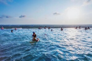 A group of people swimming in a large body of water with a clear sky in the background.