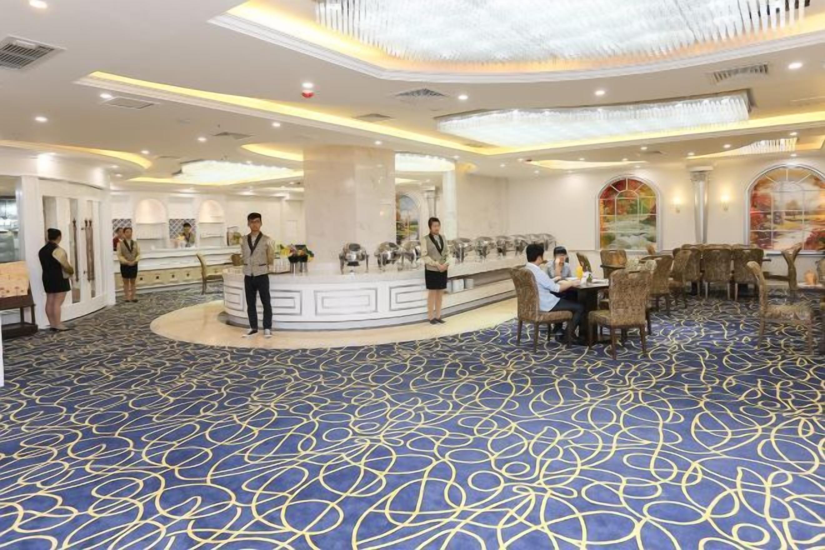 A hotel lobby with a reception desk, seating area, and a patterned carpet.