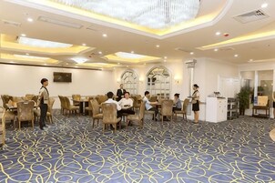 Un salón de conferencias de hotel con mesas redondas, sillas y un atril central.