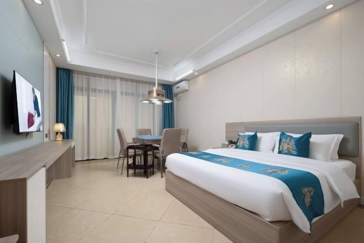 Une chambre d’hôtel avec un lit, un bureau, une chaise et un téléviseur fixé au mur.