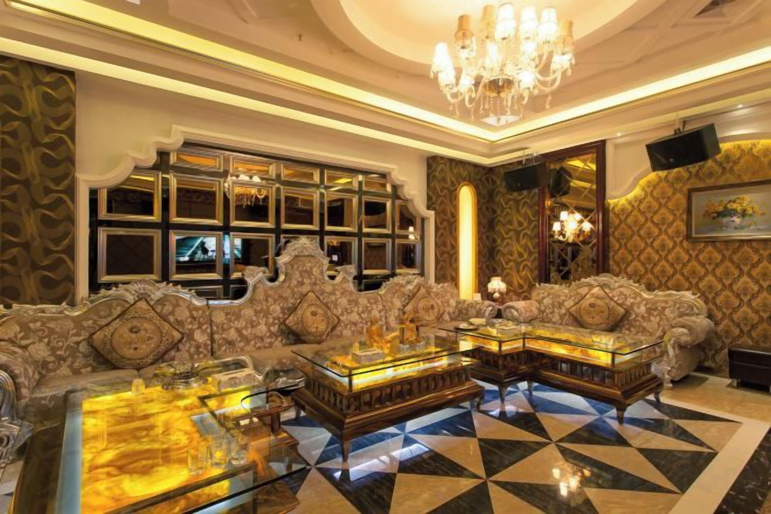 A luxurious lobby with ornate furniture, a chandelier, and a large television screen.