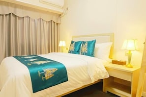 A hotel room with a bed, two bedside lamps, a nightstand, and a curtain. - Yijia International Hotel (Wenchang)