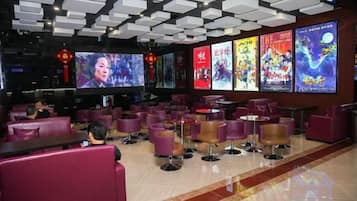 A restaurant with multiple seating areas, including booths and tables, with a modern ceiling design and wall-mounted screens displaying content.