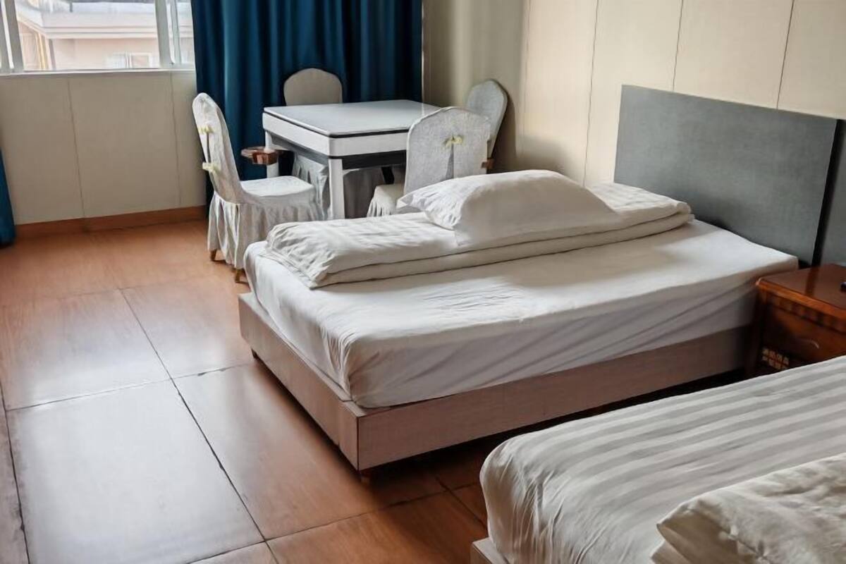 A hotel room with a bed, a desk, a chair, and a window with curtains.