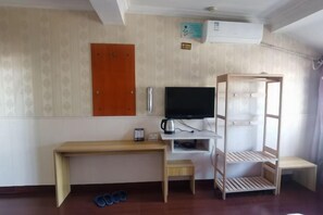 A room with a wooden desk, a television, a shelf with a kettle, a bench, and a wooden rack. - Liya Business Hotel (Sanmen)