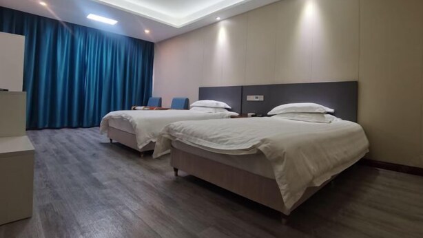 Habitación de hotel con dos camas, un escritorio y un ventanal grande con cortinas.