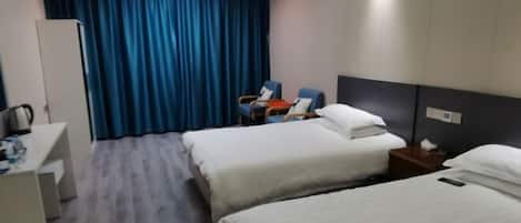 A hotel room with two beds, a desk, a chair, and a curtain.