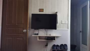 A room with a TV mounted on the wall, a shoe rack below it, and a door labeled '202'.