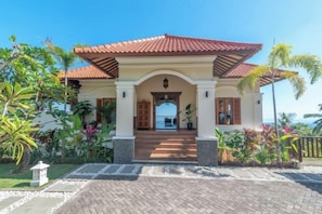 A building with a red-tiled roof, a covered entrance, and a paved walkway leading to the entrance. - Villa Mata Hari (Bali)