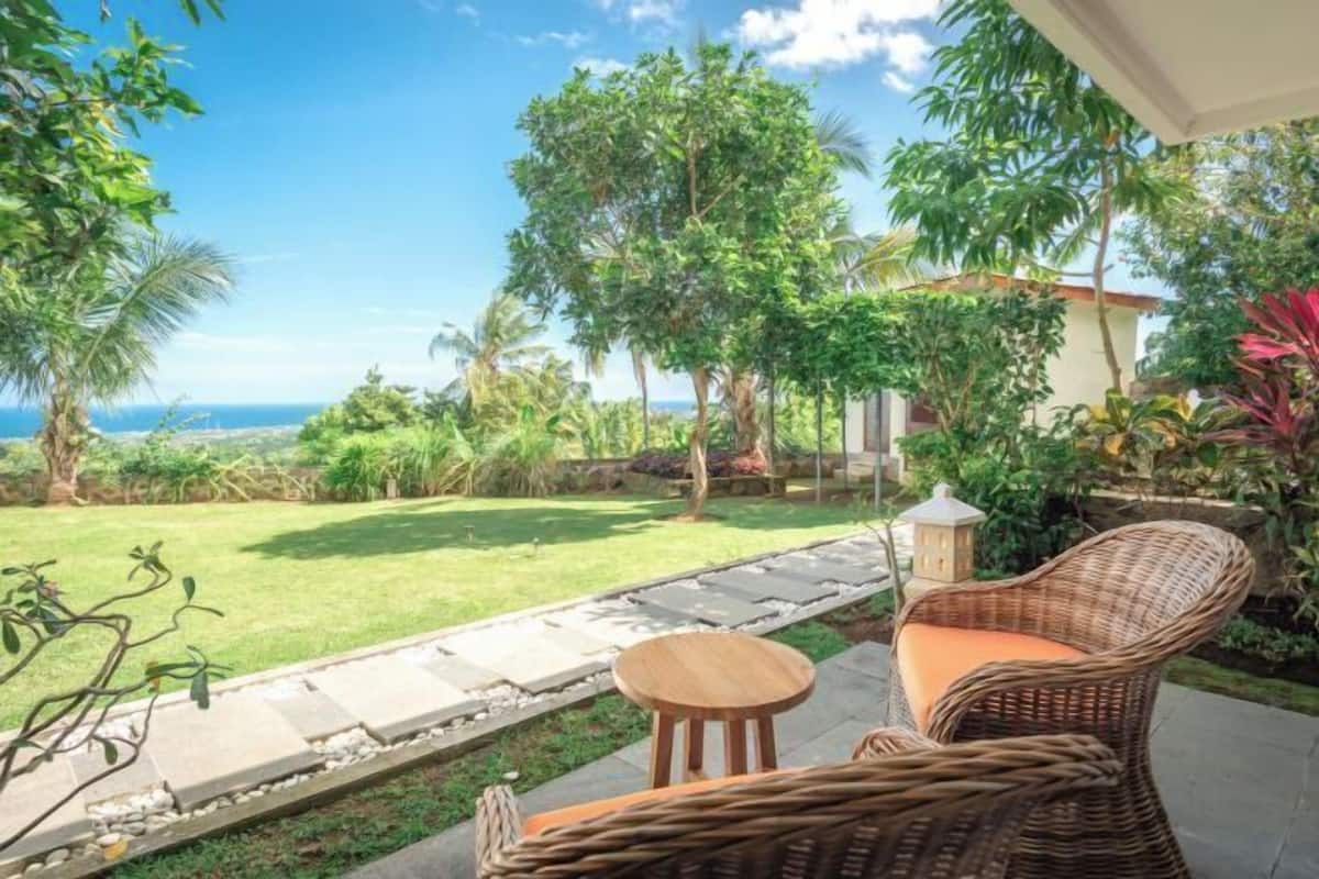A patio with wicker furniture, a small table, and a view of the ocean.