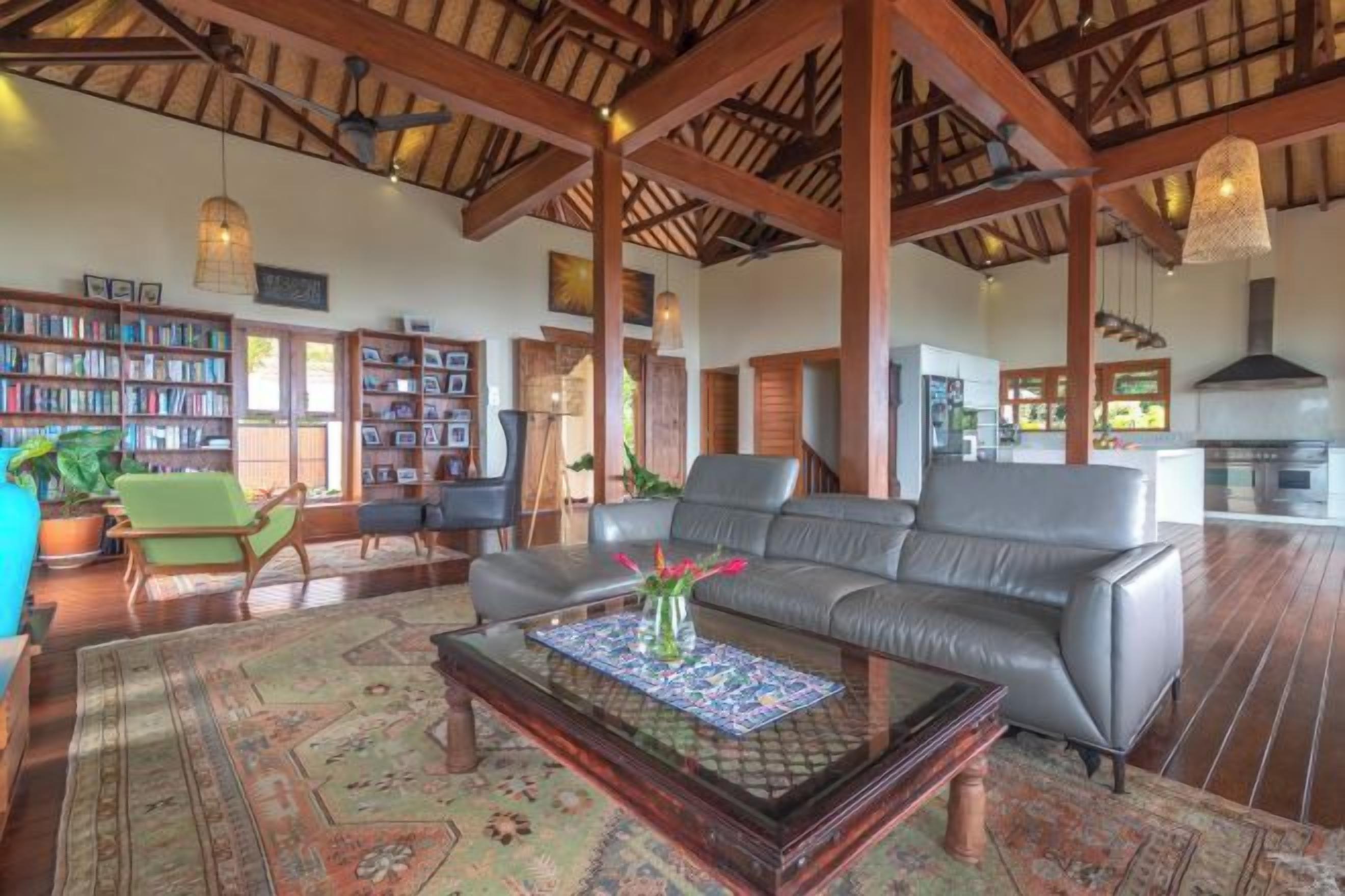 A spacious living room with a leather sofa, a coffee table, and a bookshelf.