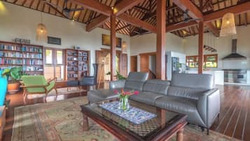 A spacious living room with a leather sofa, a coffee table, and a bookshelf.