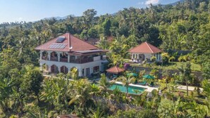 A large house with a red roof, surrounded by lush greenery and a pool. - Villa Mata Hari (Bali)