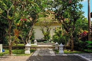 A garden pathway leading to a building with a white facade, surrounded by lush greenery and white lanterns. - Villa Mata Hari (Bali)