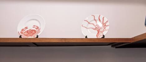 Une étagère de cuisine avec trois bols blancs et deux assiettes décoratives ornées de motifs rouges.