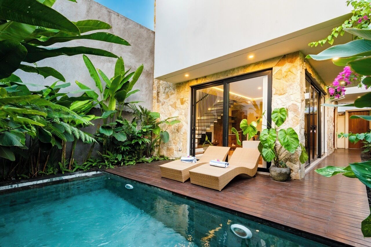 A modern outdoor pool area with lounge chairs and a stone wall.