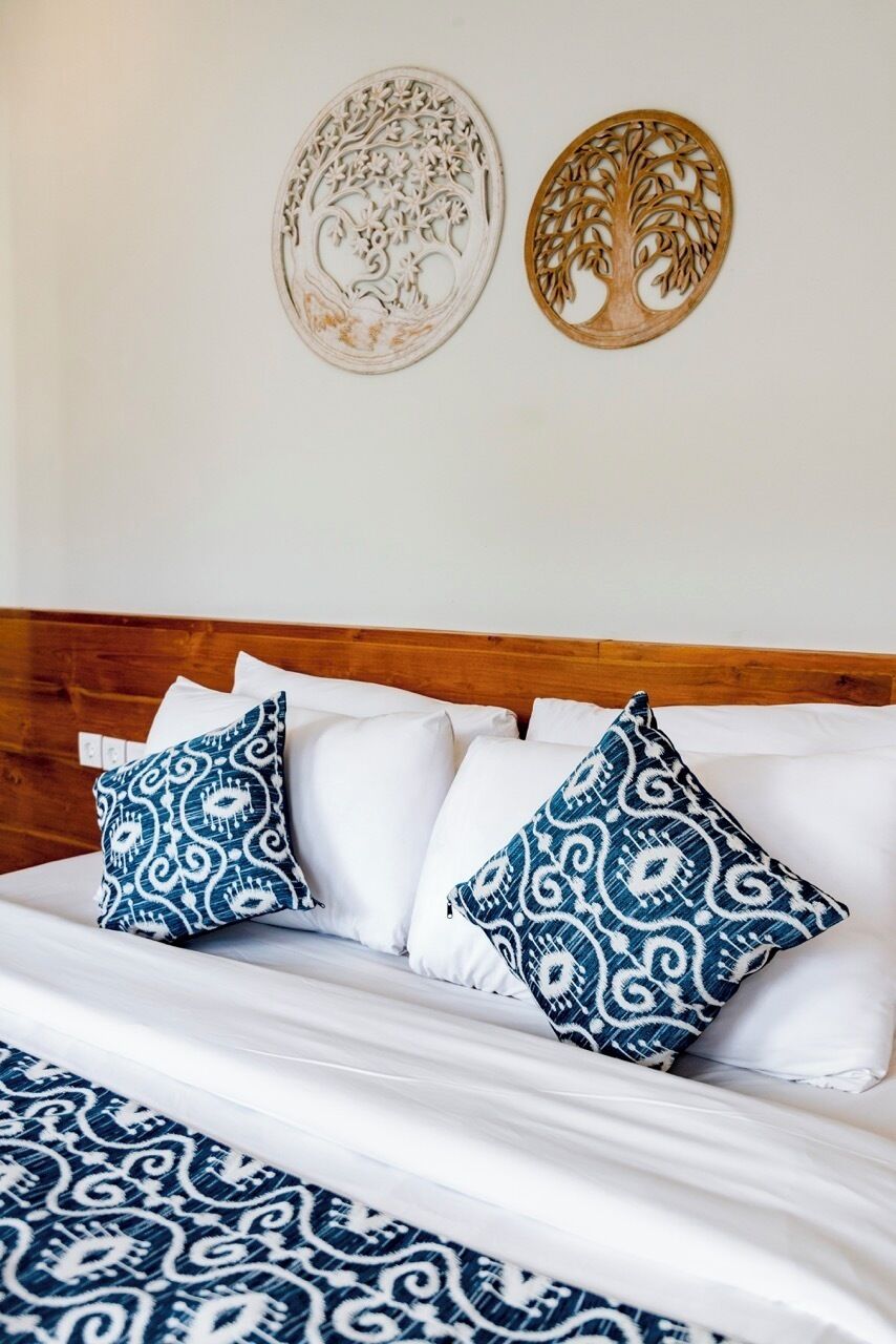 Una cama con ropa de cama de diseño blanco y azul, un cabecero de madera y dos adornos en la pared.