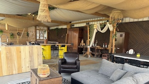A cozy, rustic interior with a wooden bar, seating area, and a dining table.