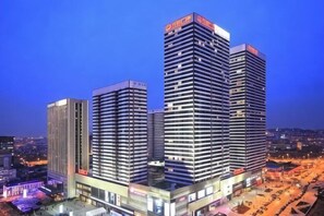 A multi-story hotel with a modern design, featuring a prominent entrance and a large parking area. - Qingdao Lanting Holiday Apartment (Qingdao)