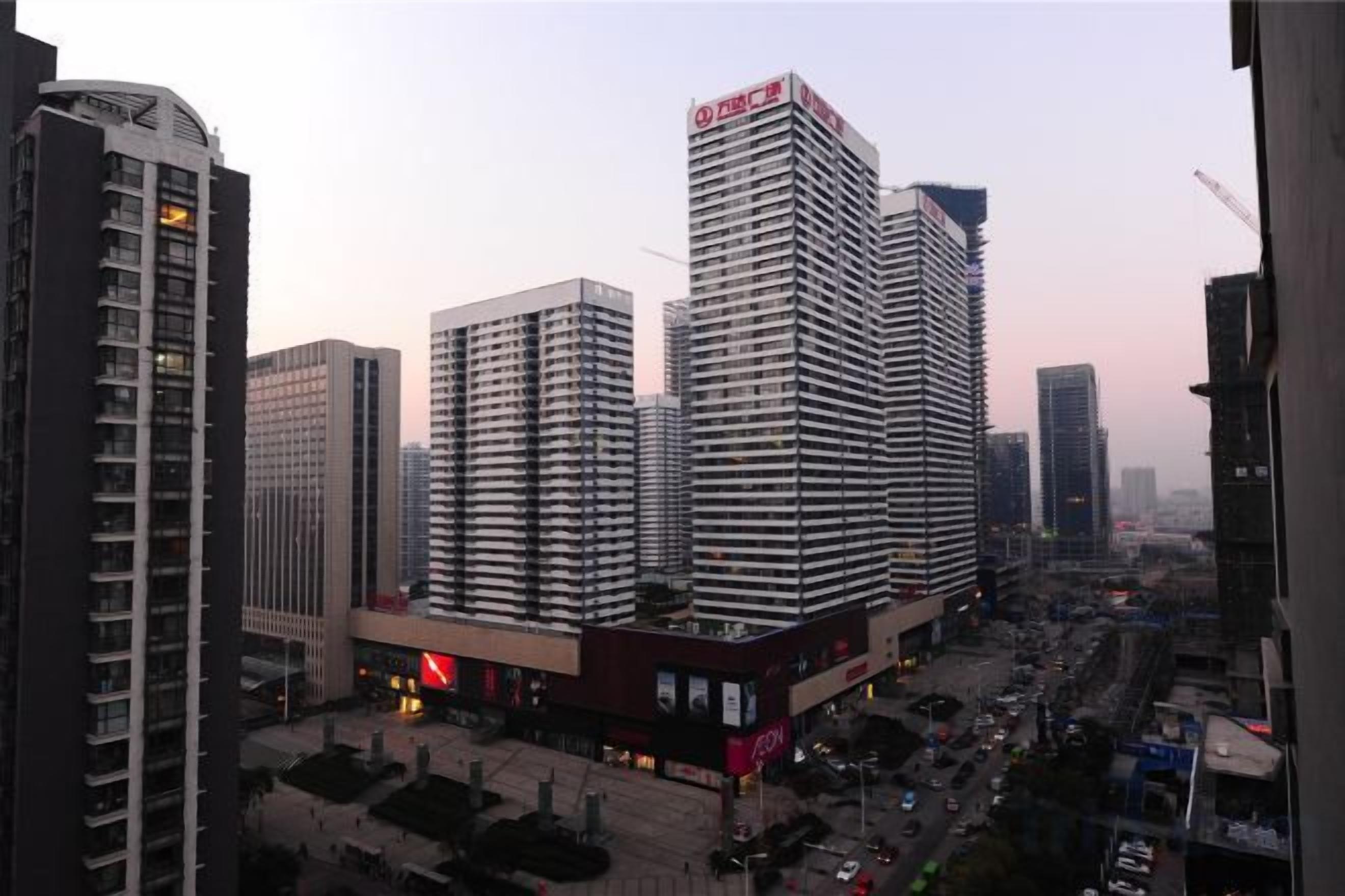 A cityscape with high-rise buildings, a busy street, and a clear sky.