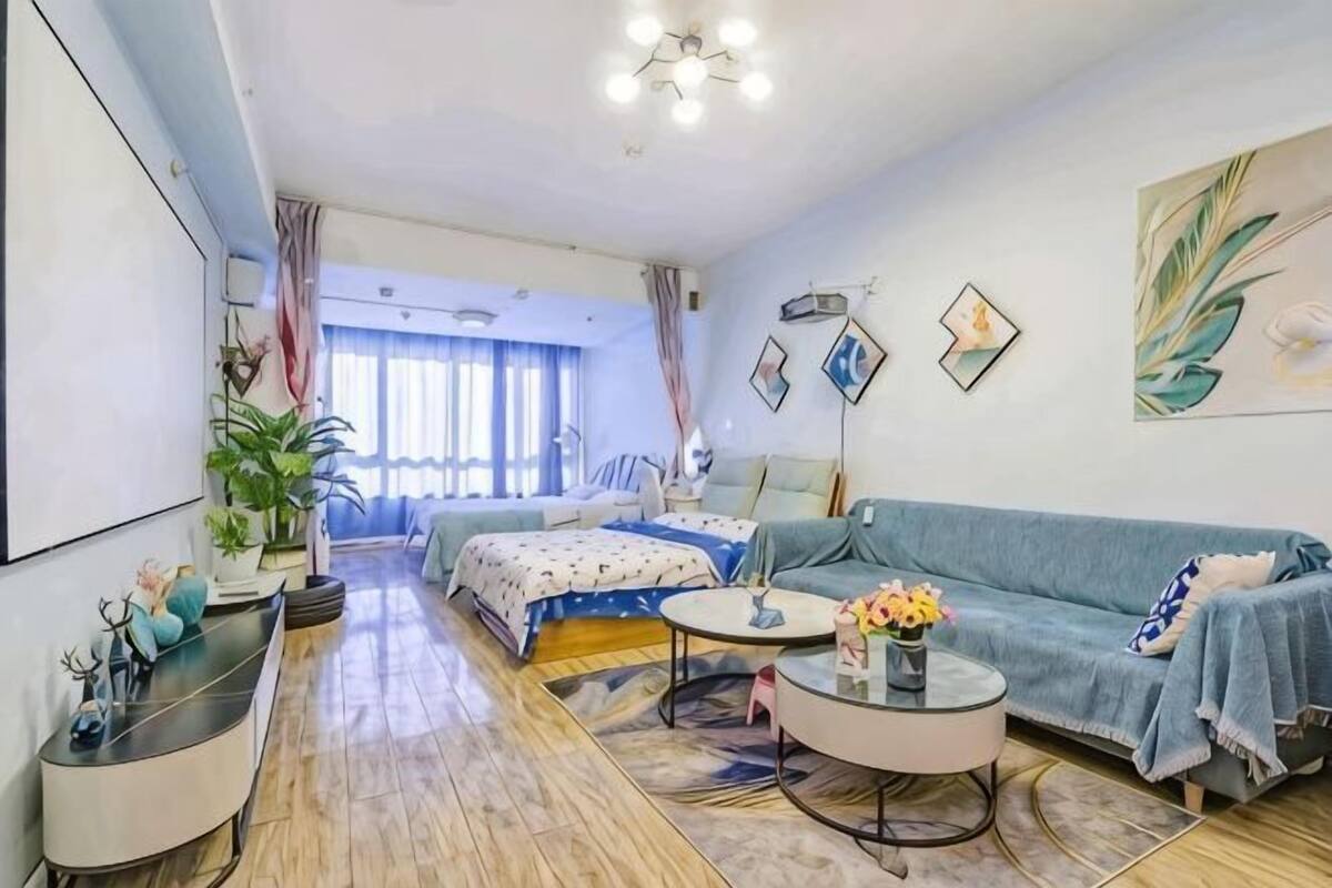 A modern living room with a sofa, coffee table, and a bed in the background.
