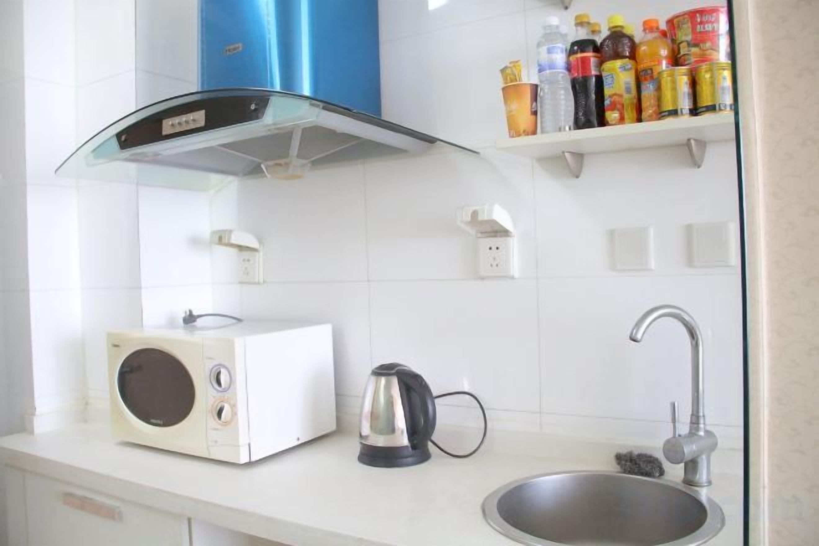 Een keuken met een magnetron, waterkoker en spoelbak.