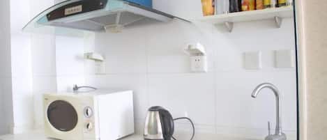 A kitchen with a microwave, kettle, and sink.
