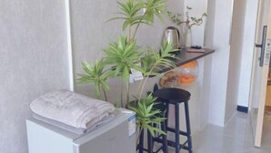 A small kitchenette with a towel on a counter, a coffee maker, and a potted plant.