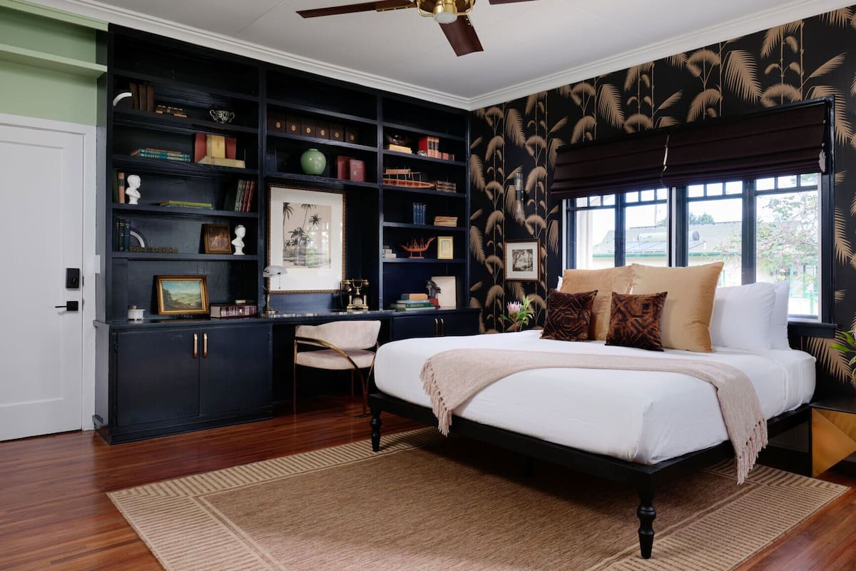 A bedroom with a bed, a desk, and a bookshelf.