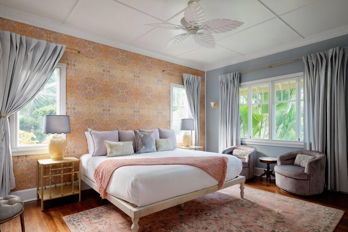 A bedroom with a four-poster bed, two bedside tables with lamps, a small round table, and a chair.