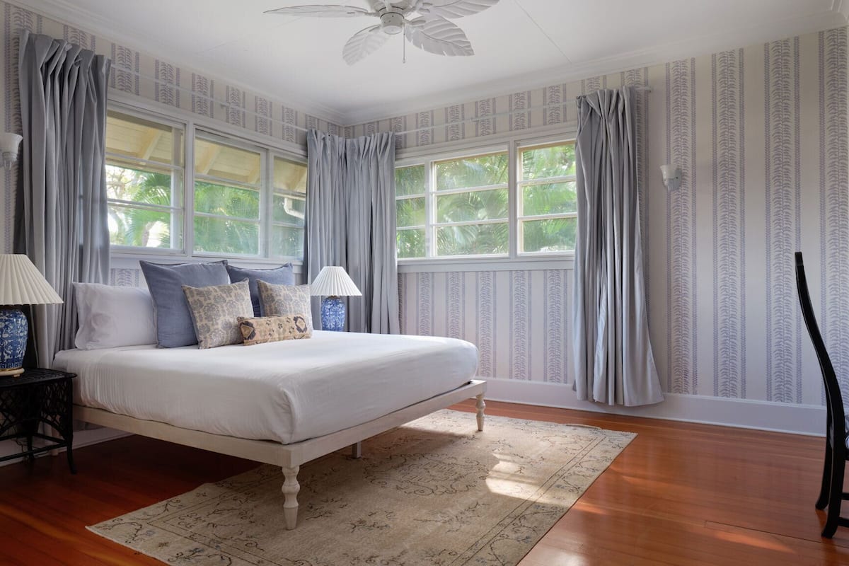 A bedroom with a bed, two bedside tables, a chair, and a ceiling fan.